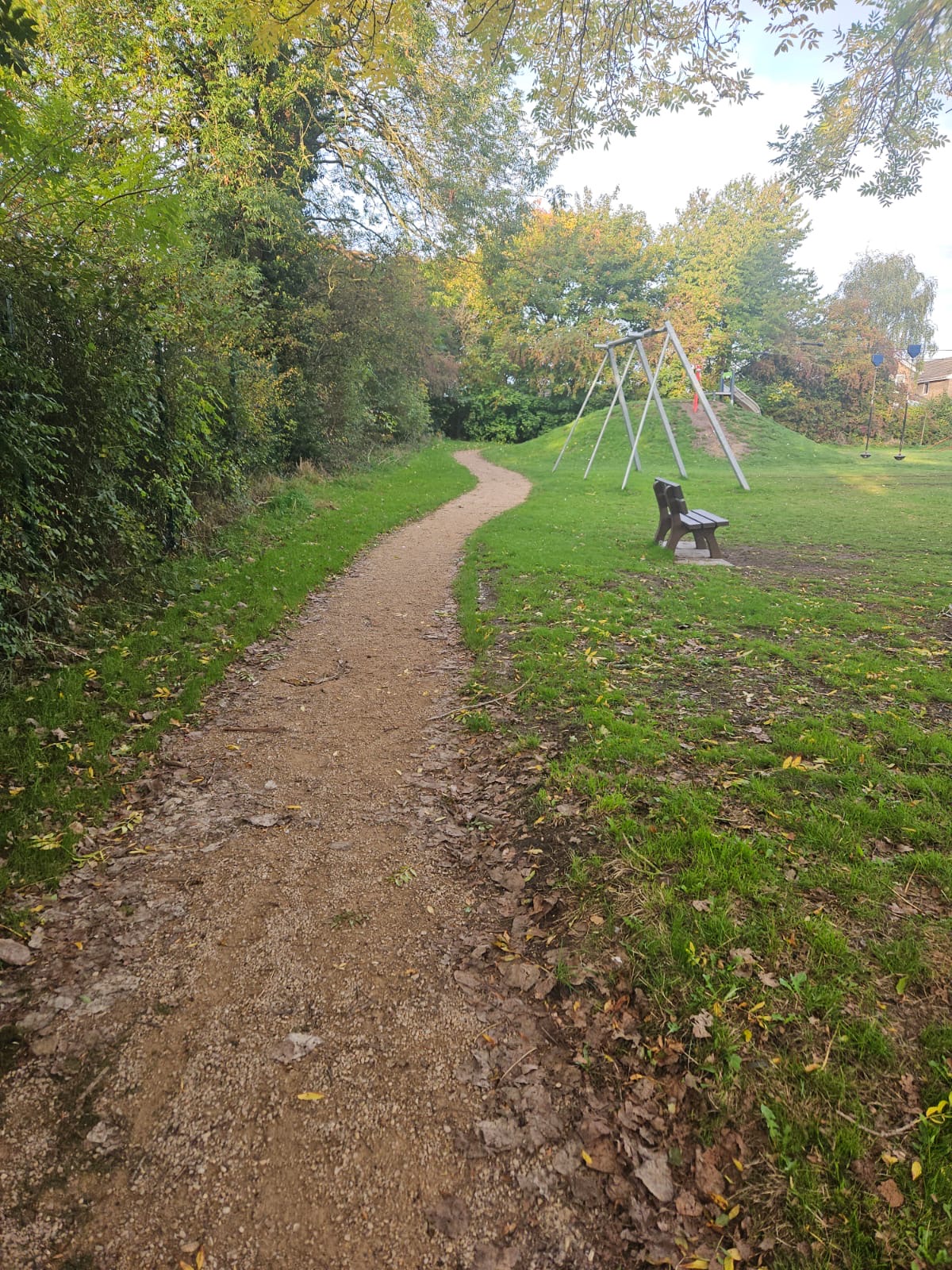 Gravel footpath laid through a public green space, providing a defined walking route beside grassed areas and trees.